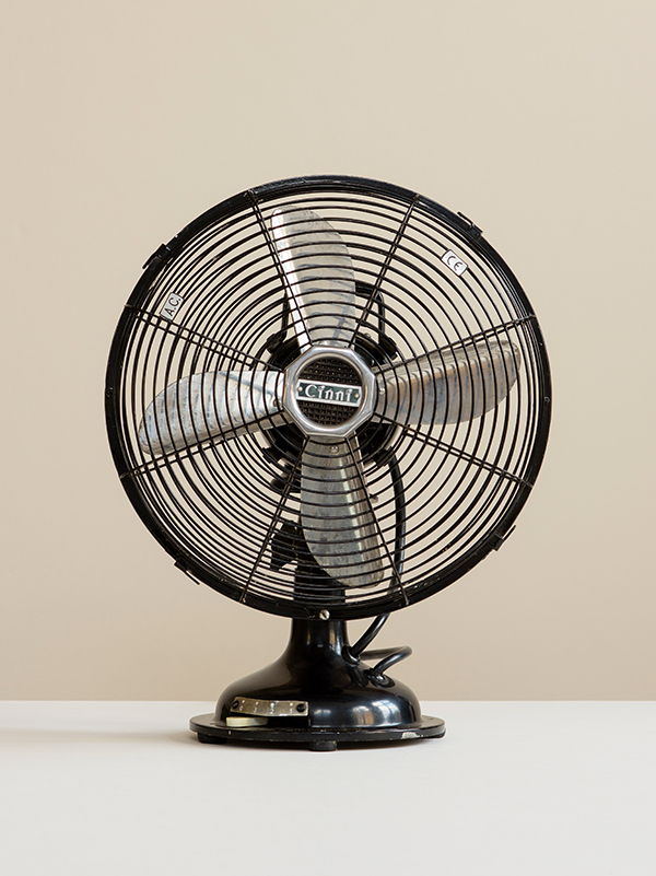 Photograph of an Original Cinni Black Desk Fan with silver blades on a white surface with cream background