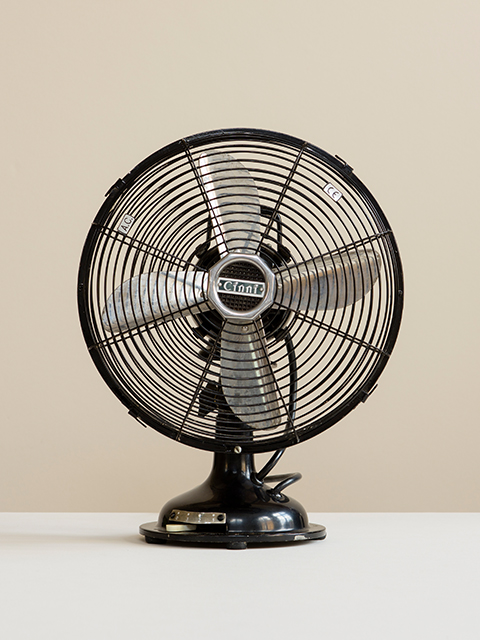 Photograph of an Original Cinni Black Desk Fan with silver blades on a white surface with cream background